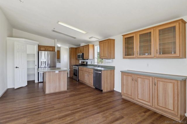 a kitchen with stainless steel appliances granite countertop wooden cabinets a refrigerator a sink a stove a microwave and wooden floors