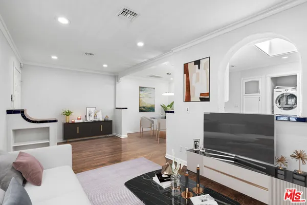 a living room with furniture a flat screen tv and kitchen view