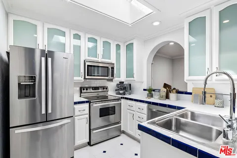 a kitchen that has a sink cabinets and stainless steel appliances