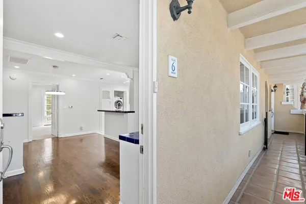 a view of a hallway with wooden floor and a bathroom