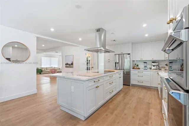 a large kitchen with kitchen island a stove a sink dishwasher and white cabinets with wooden floor