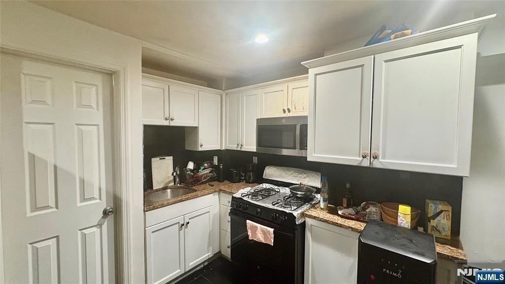 17 Cleveland Avenue, Unit 2 Harrison, NJ 07029 - Photo 4 of 12 a kitchen with stainless steel appliances white cabinets and a stove top oven