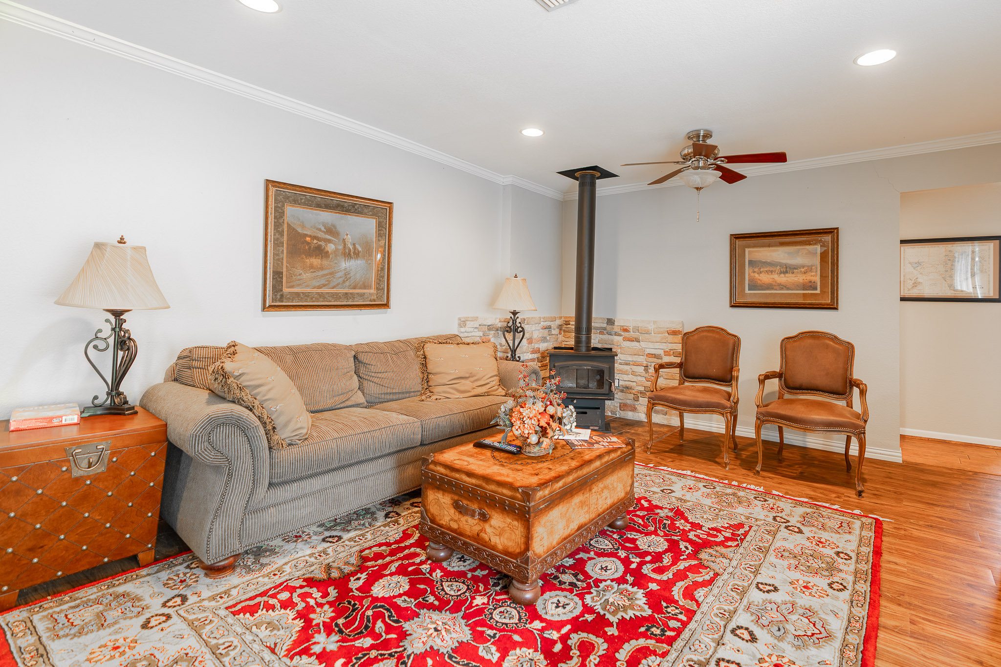 2145 County Road 320 Lohn, TX 76852 - Photo 4 of 40 Living area with a wood stove, ornamental molding, wood finished floors, a ceiling fan, and recessed lighting