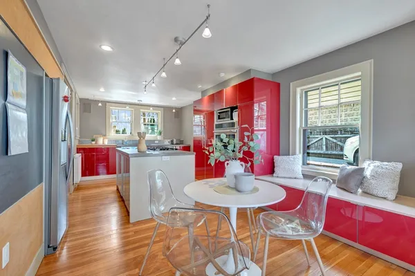 a kitchen with stainless steel appliances kitchen island granite countertop a dining table chairs and a refrigerator