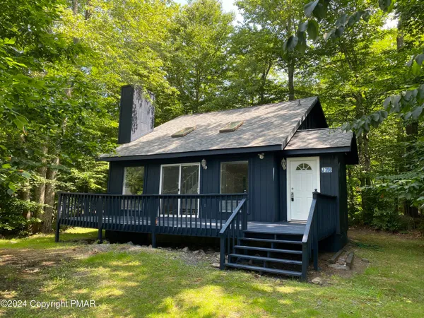 a view of a house with a wooden deck and a small yard