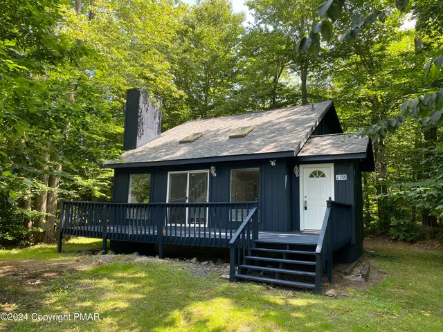 a view of a house with a wooden deck and a small yard