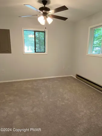 an empty room with windows and fan