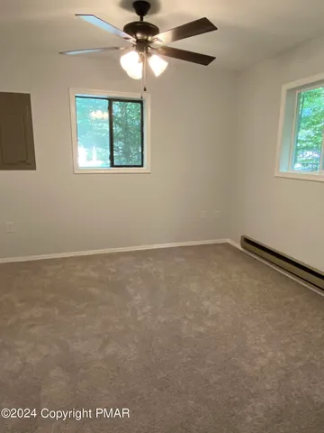 an empty room with windows and fan