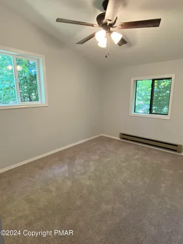 en empty room with windows and ceiling fan