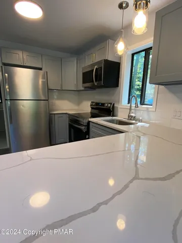 a kitchen with stainless steel appliances granite countertop a refrigerator a stove a sink dishwasher and a refrigerator with wooden floor