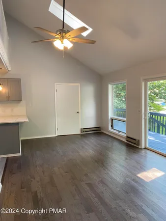 a view of an empty room with window and wooden floor