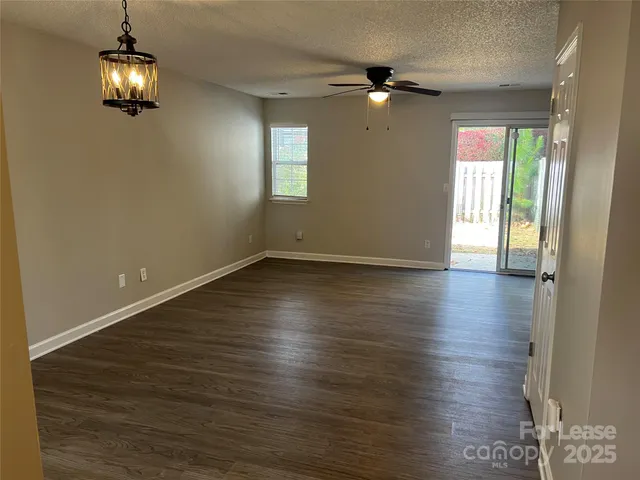 an empty room with wooden floor and chandelier