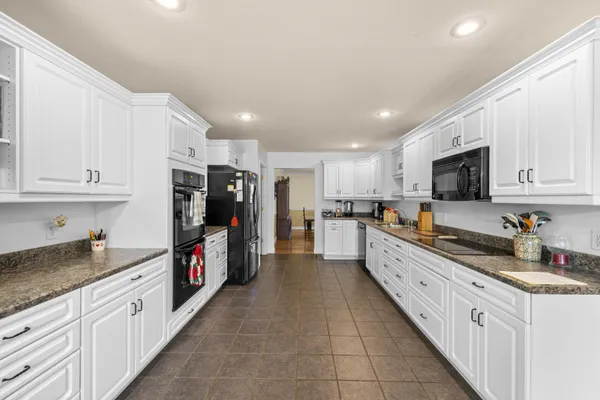 a kitchen with stainless steel appliances granite countertop a stove and white cabinets