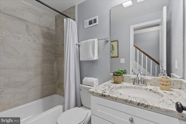 a bathroom with a granite countertop sink a toilet and shower
