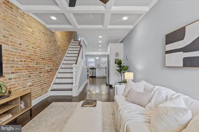 a living room with couches and kitchen view with wooden floor