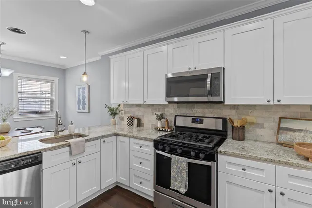a kitchen with stainless steel appliances granite countertop white cabinets granite counter tops and a wooden floors