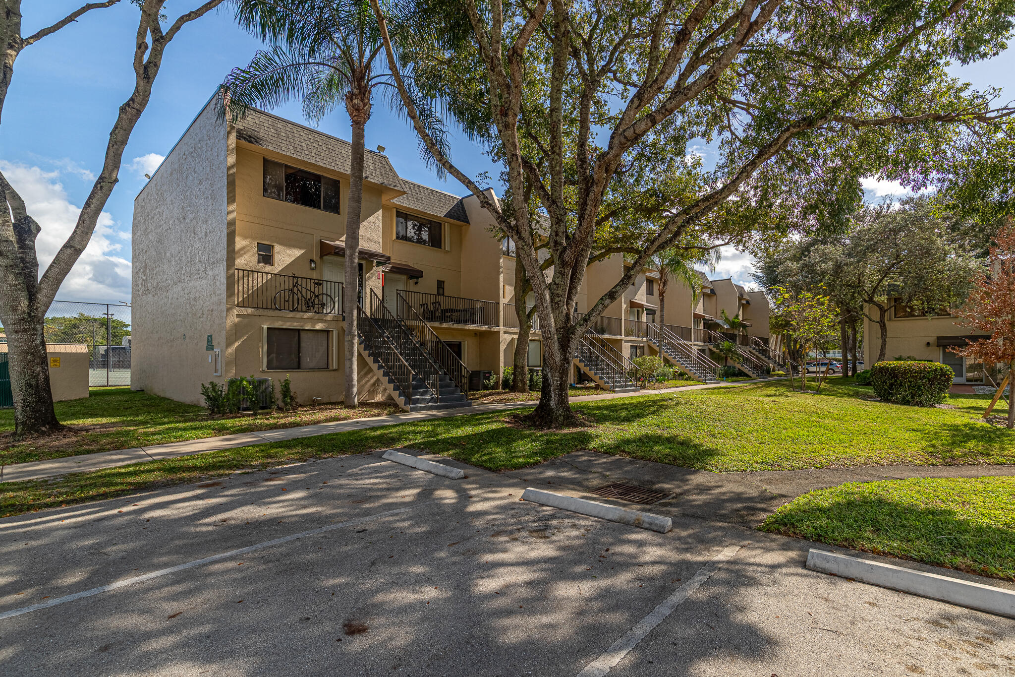105 Deer Creek Road Deerfield Beach, FL 33442 - Photo 18 of 18 a view of a white house next to a yard with big trees
