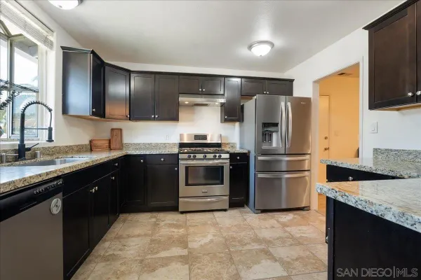 a kitchen with stainless steel appliances granite countertop a stove a sink and a microwave