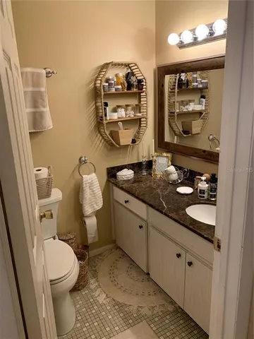 a bathroom with a granite countertop toilet sink and mirror