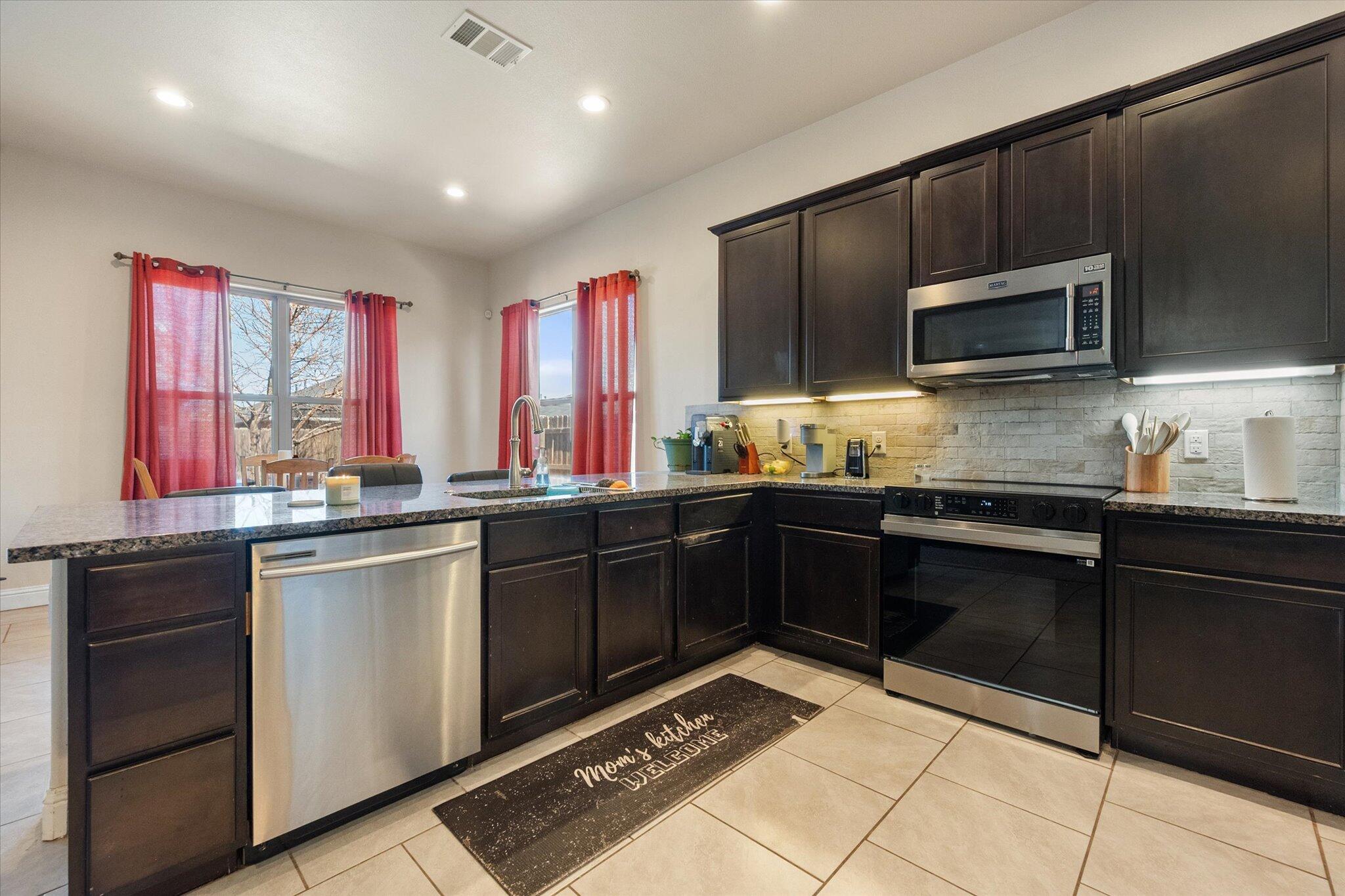7038 95th Street Lubbock, TX 79424 - Photo 2 of 23 a kitchen with stainless steel appliances a stove sink microwave and cabinets