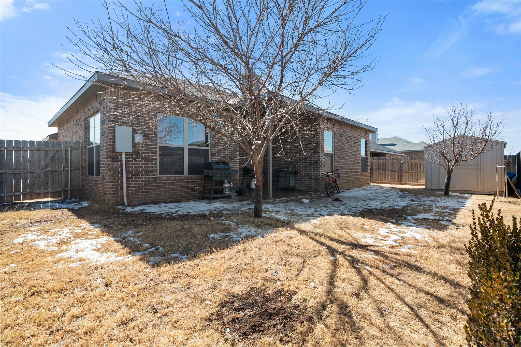 7038 95th Street Lubbock, TX 79424 - Photo 22 of 23 a backyard of a house with large tree and wooden fence