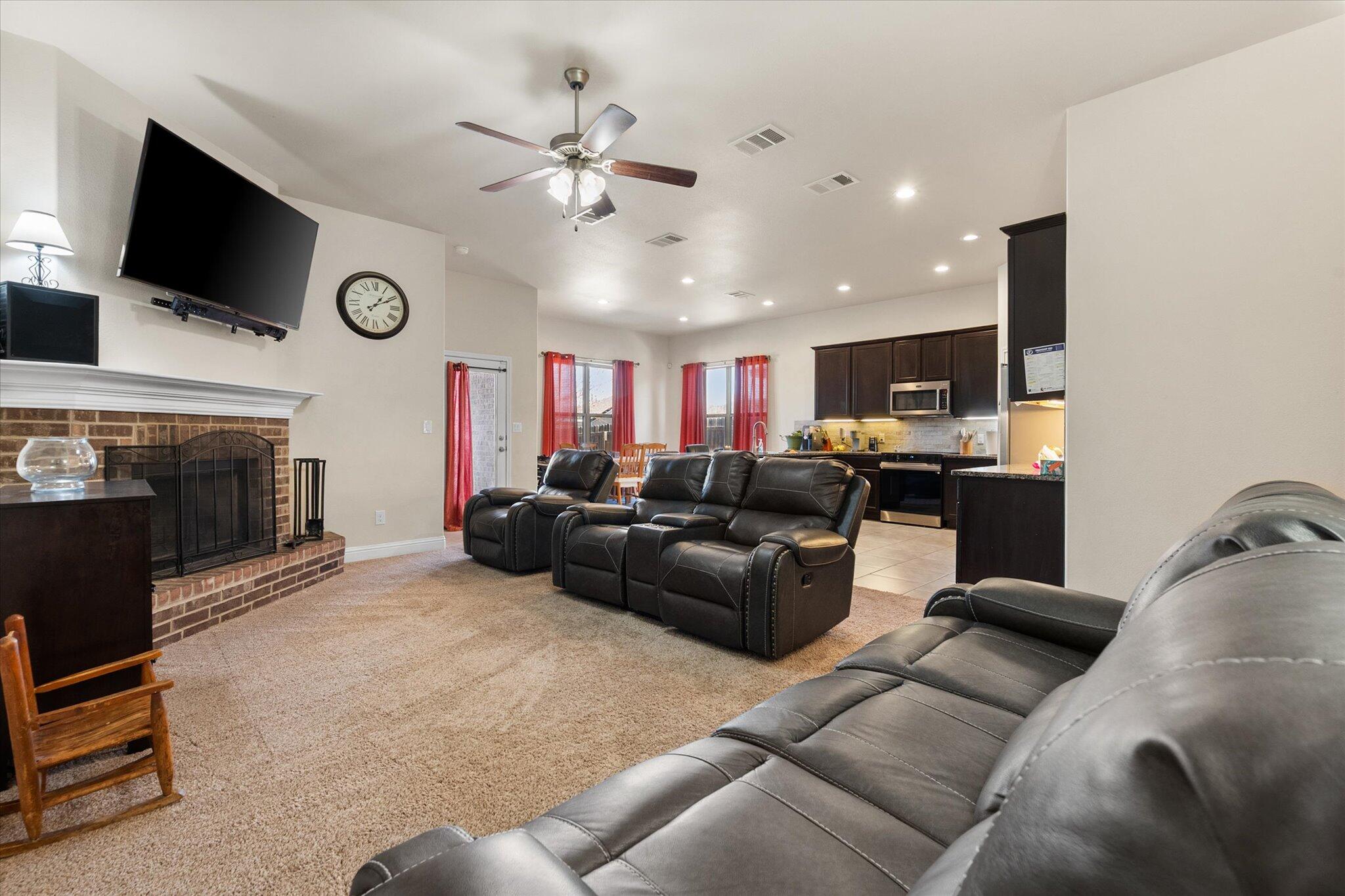 7038 95th Street Lubbock, TX 79424 - Photo 7 of 23 a living room with furniture a flat screen tv and a fireplace