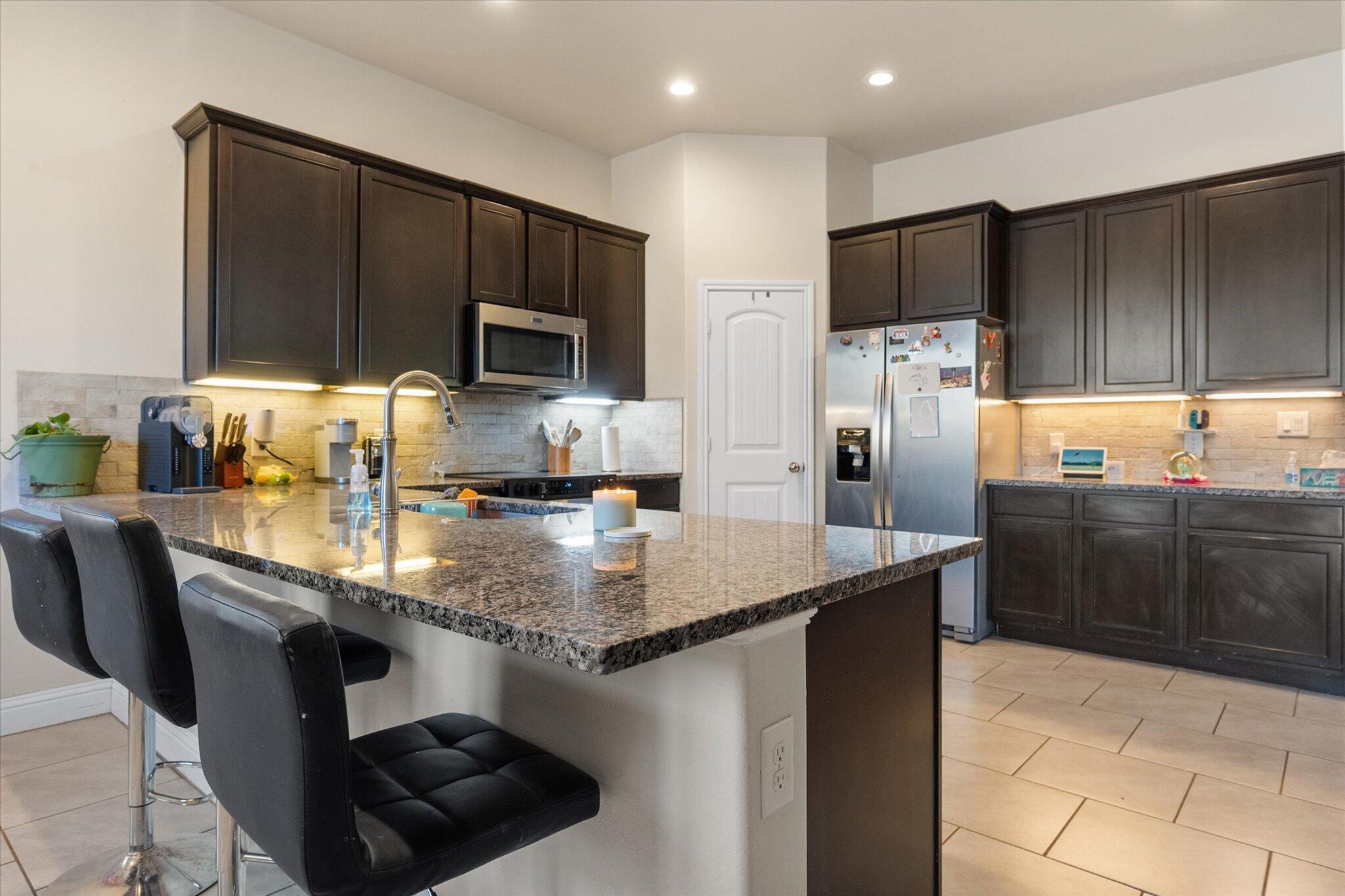 7038 95th Street Lubbock, TX 79424 - Photo 10 of 23 a kitchen with stainless steel appliances a sink a stove a refrigerator and cabinets