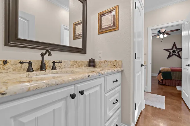 a en suite bathroom with a granite countertop sink and a mirror