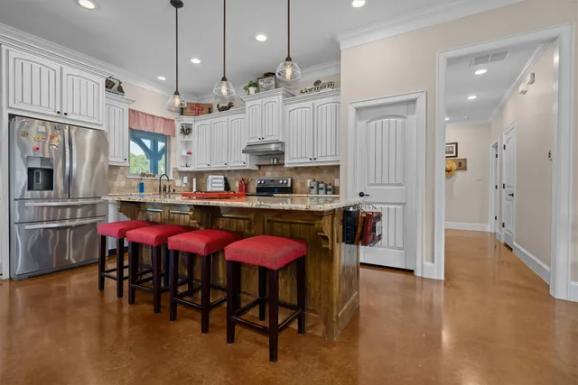 a kitchen with stainless steel appliances kitchen island granite countertop a table chairs and a refrigerator