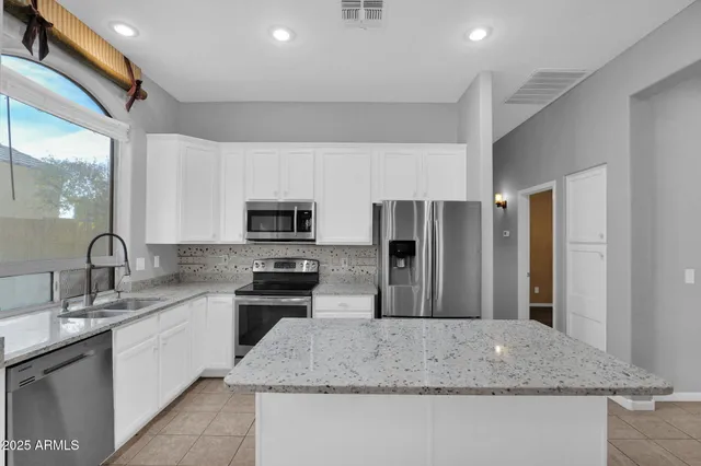 a kitchen with stainless steel appliances granite countertop a sink a stove and a refrigerator