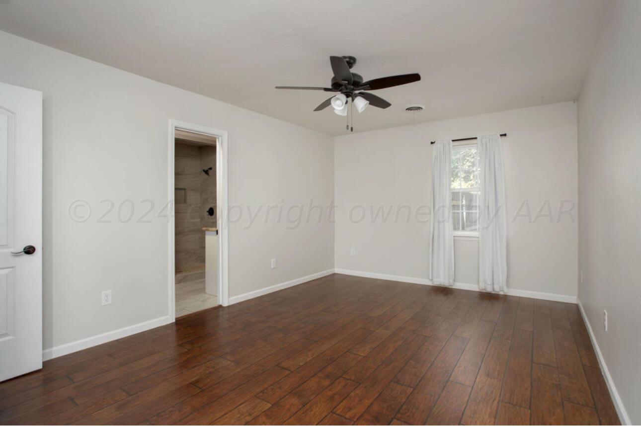 4818 Arden Road Amarillo, TX 79110 - Photo 19 of 29 an empty room with wooden floor a ceiling fan and windows