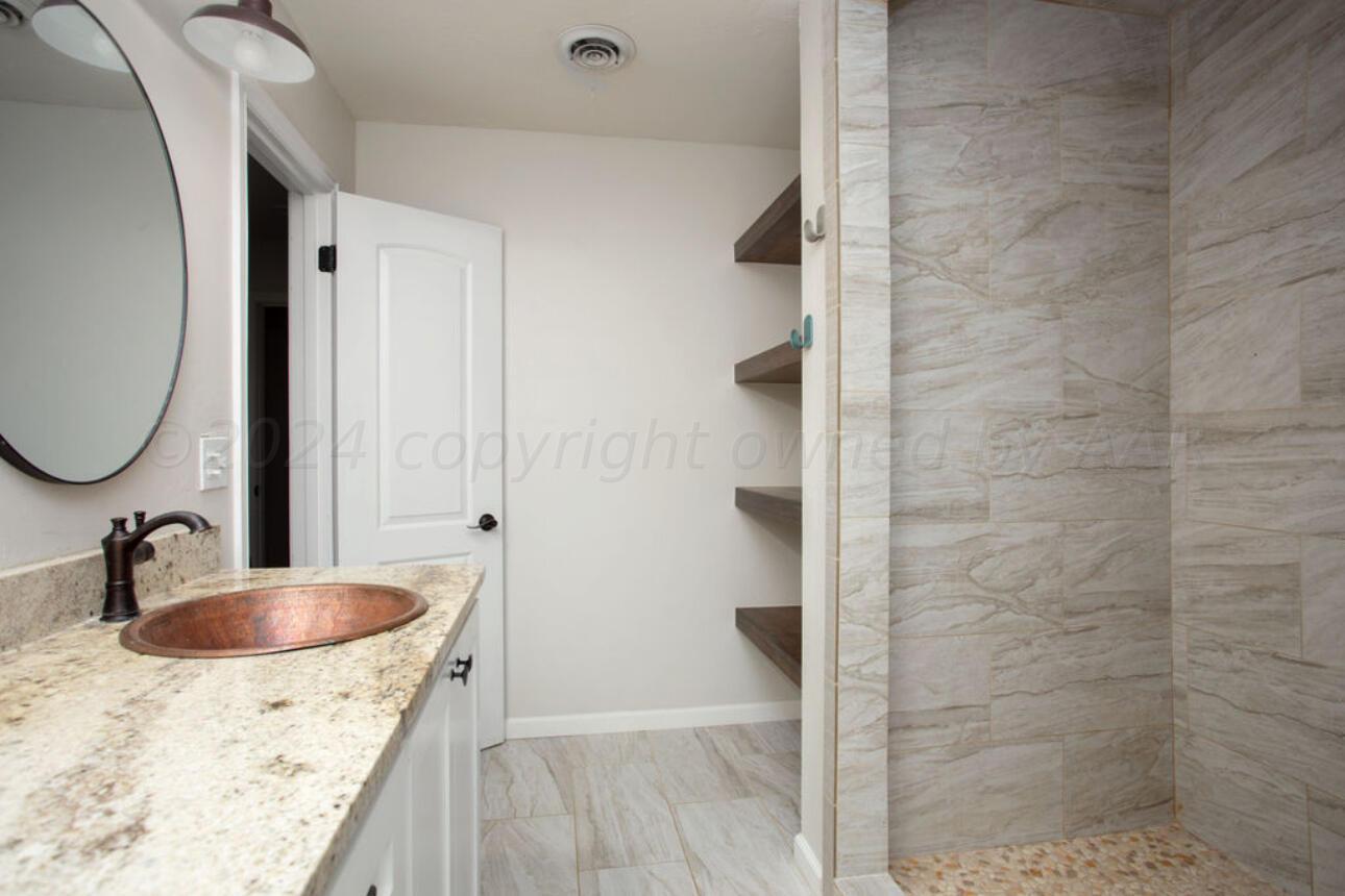 4818 Arden Road Amarillo, TX 79110 - Photo 21 of 29 a bathroom with a granite countertop sink a mirror and shower