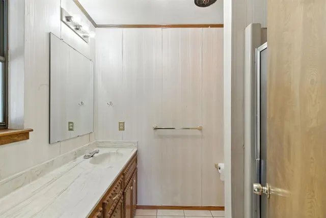 a bathroom with a granite countertop sink a mirror and a shower