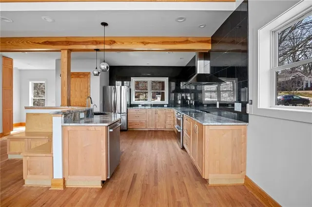 a kitchen with stainless steel appliances wooden floor and wooden cabinets