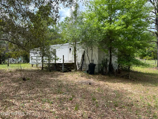 a view of backyard with large trees and wooden fence