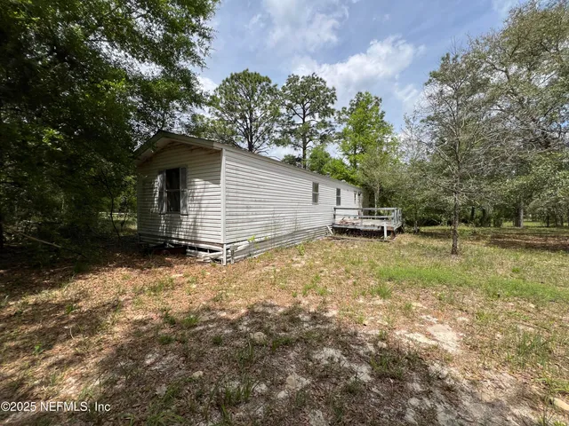 a backyard of a house with lots of plants and large trees