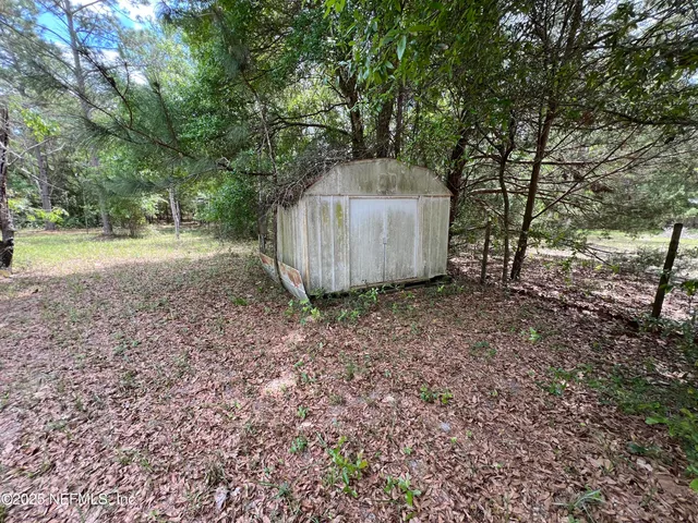 a view of a back yard of the house with a bench