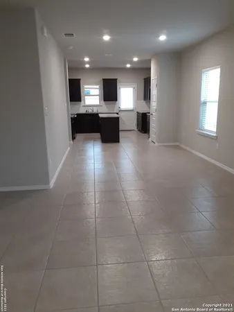 a view of empty room with kitchen and window