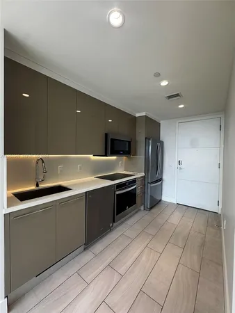 a large kitchen with a sink and dishwasher a stove top oven with wooden floor