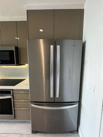 a metallic refrigerator freezer sitting inside of a kitchen