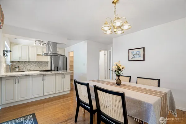 a kitchen with stainless steel appliances a dining table chairs and white cabinets