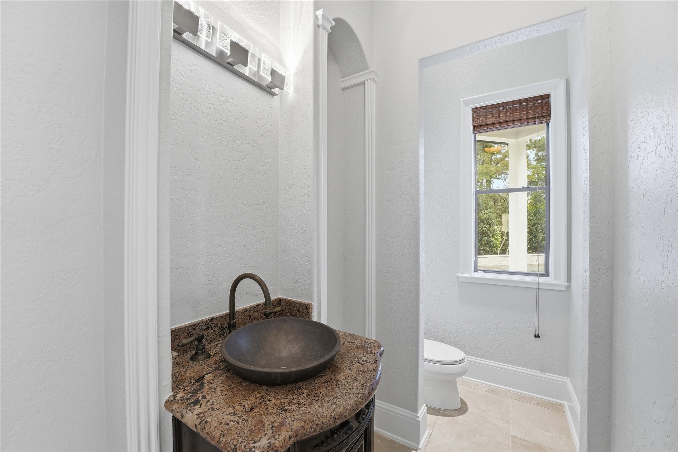 70 Quail Rock Place The Woodlands, TX 77381 - Photo 13 of 46 a bathroom with a granite countertop sink a toilet and a window