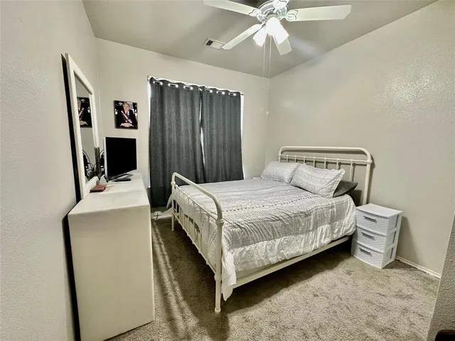 a bedroom with a bed table and flat screen tv