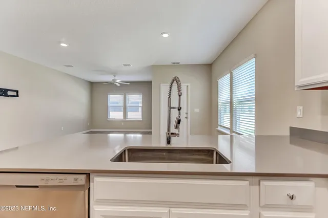 a view of entryway with kitchen island a ceiling fan and a window