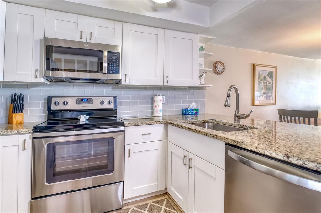 60 Gulf Boulevard, Unit 204 Indian Rocks Beach, FL 33785 - Photo 7 of 45 a kitchen with granite countertop white cabinets stainless steel appliances and a sink