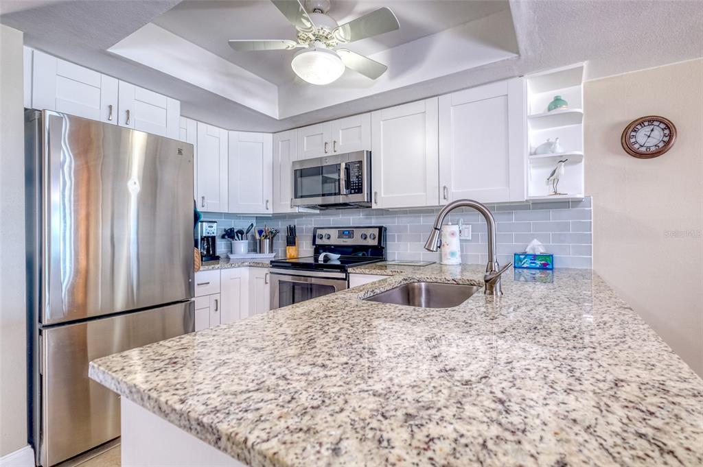 60 Gulf Boulevard, Unit 204 Indian Rocks Beach, FL 33785 - Photo 8 of 45 a kitchen with stainless steel appliances granite countertop a sink refrigerator and microwave