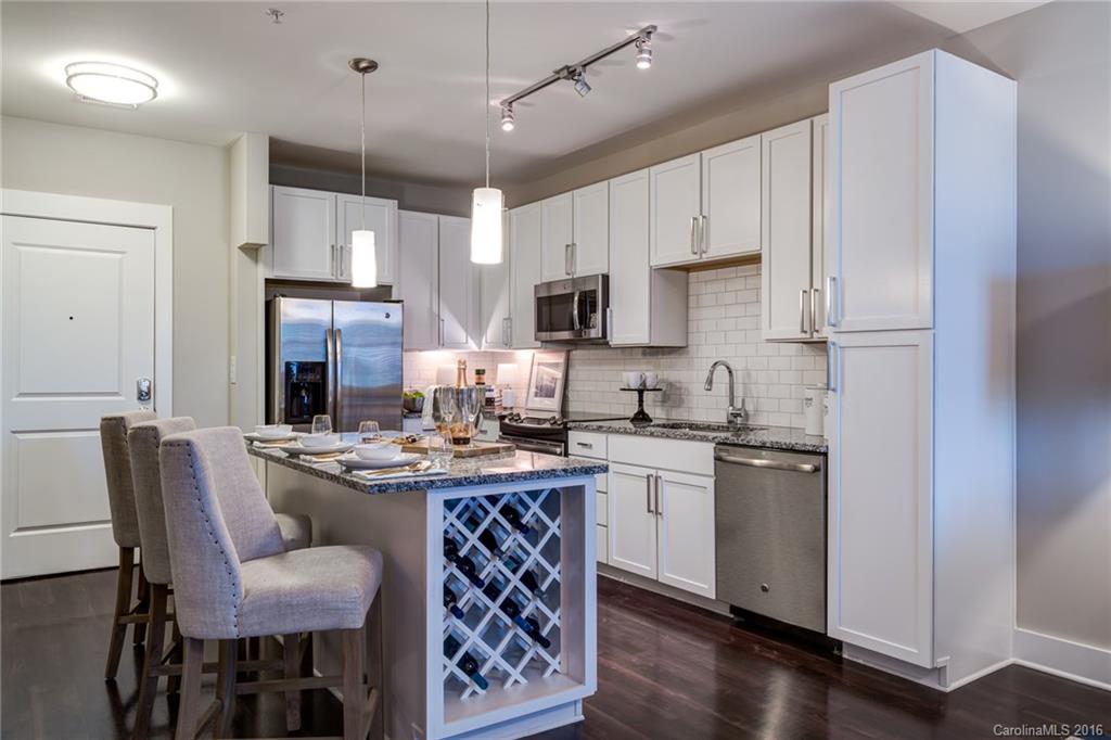 1440 Harding Place, Unit 446 Charlotte, NC 28204 - Photo 9 of 19 a kitchen with stainless steel appliances granite countertop a table chairs refrigerator and microwave