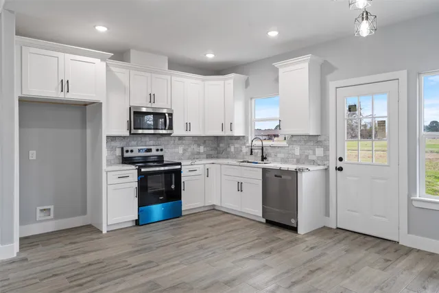a kitchen with granite countertop white cabinets and stainless steel appliances