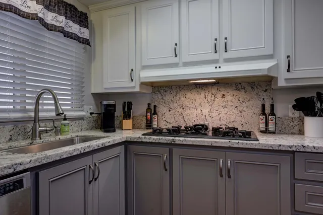 a kitchen with stainless steel appliances granite countertop a sink a stove and cabinets
