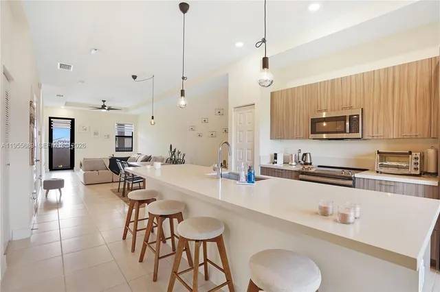 a kitchen with stainless steel appliances granite countertop a sink a stove a dining table and chairs